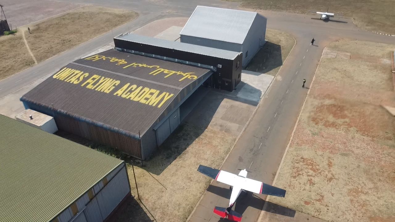 Student standing on the wing of a Unitas training aircraft